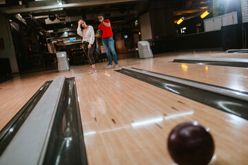 A beautiful loving caucasian couple throwing balls on the bowling alley. Boyfriend and girlfriend at the bowling club