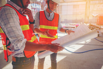 Structural engineer and foreman worker with paper work discuss, plan working for the outdoors building construction site.