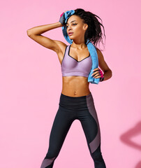 Fototapeta na wymiar Resting time. Sporty girl with towel after training. Photo of african american girl with perfect body on pink background. Strength and motivation