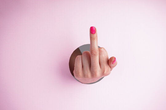Middle finger on a pink background, abusive gesture. Fuck you concept.