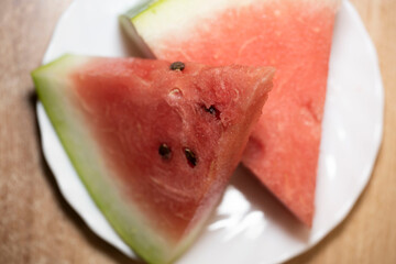 Slices of pounded juicy red watermelon on a white plate.