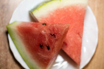 Slices of pounded juicy red watermelon on a white plate.