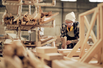 Woman carpenter working with wood at factory