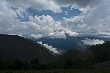 Panorama of the mountains of the Caucasus. Clouds over the rocky peaks. Snow on the rocks. Fog in the valleys after a rainstorm.