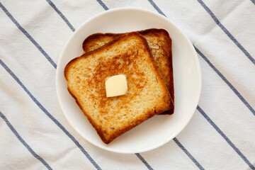Homemade Buttered Toast on a white plate, top view.