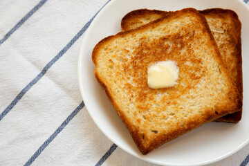 Homemade Buttered Toast on a white plate, close-up. Copy space.