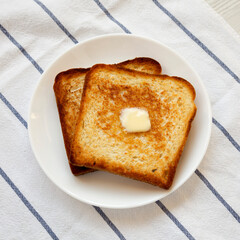Homemade Buttered Toast on a white plate, close-up.