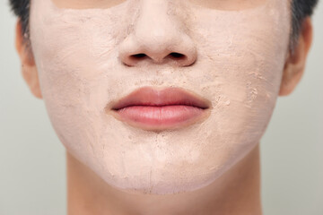 Handsome man with clay mask on his face against white background