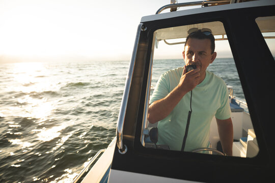A Caucasian man using a walkie-talkie on a boat 