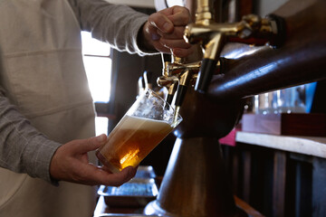 Caucasian man serving a pint of beer in a brewery