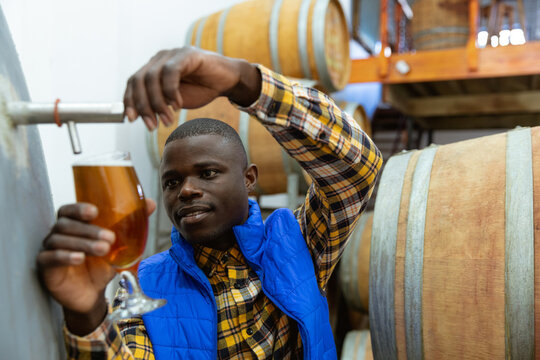 Black African American Man filling beer in glass at microbrewery