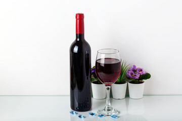 Wine bottle and wine glass on white background. Home decor with copy space for your text.