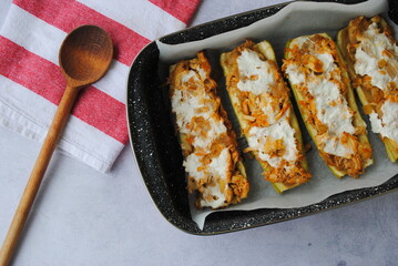 Zucchini Lunch: Stuffed Zucchini Boats with chicken, carrots, and onions, poured with Sour cream. Top view.