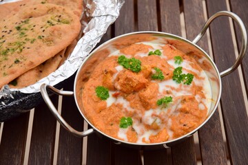 Murgh Makhani or butter chicken served with homemade whole wheat garlic Naan bread