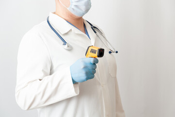 Doctor in protective mask and gloves measure temperature using infrared thermometer.