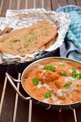 Murgh Makhani or butter chicken served with homemade whole wheat garlic Naan bread