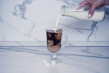 Stock image pouring milk into a hot drink