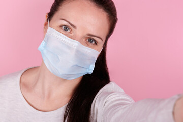 Selfie portrait of a brunette girl in a medical mask.