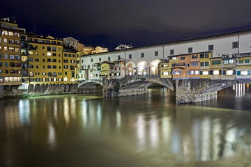Fototapeta premium The Medieval stone 'Ponte Vecchio' bridge spanning the River Arno illuminated at night