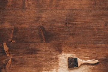 Brush with wooden handle and natural bristles against the background of painted brown wooden planks. Repairing concept. Top view. Copy, empty space for text