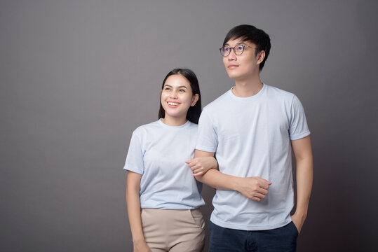 a portriat of a happy couple wearing blue shirt is hugging each other in grey background studio