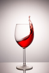 A splash of red wine in a glass on a white background