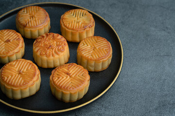 Moon cakes for the Mid-Autumn Festival are placed on a black plate with gold trim
