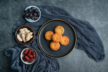 A plate of moon cakes for Mid Autumn Festival.Moon cakes for the Mid-Autumn Festival are placed on a black plate with gold trim