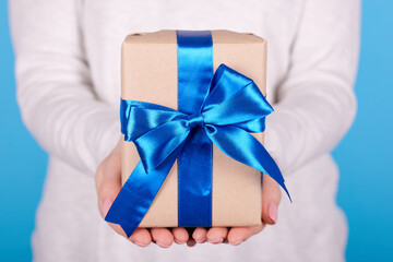 Present box with blue ribbon in hand.