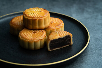 Obraz na płótnie Canvas Moon cakes for the Mid-Autumn Festival are placed on a black plate with gold trim