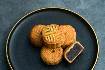 Moon cakes for the Mid-Autumn Festival are placed on a black plate with gold trim