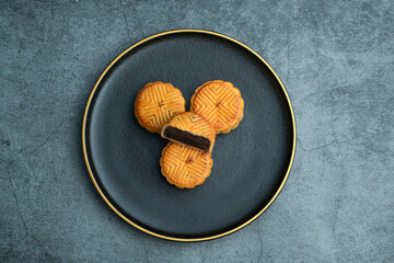 Moon cakes for the Mid-Autumn Festival are placed on a black plate with gold trim