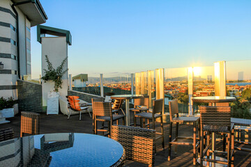 Cafe on the roof. Recreation area with modern rattan furniture: tables and chairs on a high terrace...