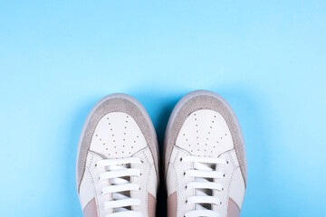 Female sneakers on blue background. Flat lay, top view minimal background. Fashion blog or magazine concept