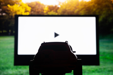 Drive-in theater or drive in cinema, open air movie. Car silhouette on the background of a large...