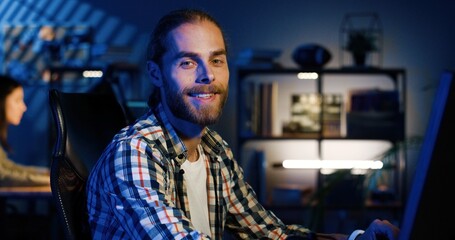 Portrait of professional video editor editing video on his personal computer with two displays in modern video studio. Young man works with headphones