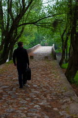 Young man carry guitar bag while walking through the forest