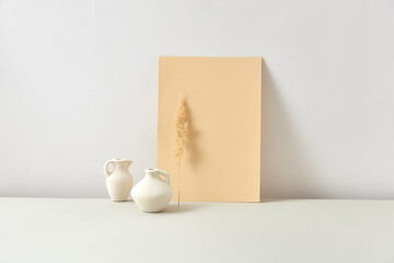 Eco composition from ceramic vases with dry twig and vertical paper sheet.