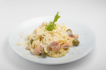 Tagliatelle pasta with seafood, olives, arugula and grated parmesan cheese. Beautifully served on a white plate, shot on a white background. For use in the online menu