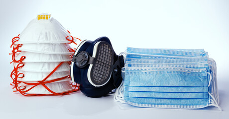 Stack of medical masks with respirator on white background