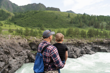 father and son on the shore of mountain river