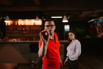 A young beautiful caucasian woman and a man are playing darts. Love and recreation