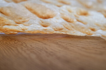 Sheet of Traditional thin lavash  bread on a wooden table. The bottom view of the pita bread, macro. Traditional Turkish/Armenian flatbread, Yufka Bread or philo dough bread -YUFKA EKMEK.