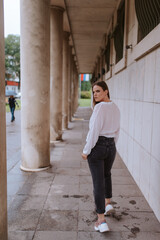 A beautiful young caucasian girl in front of a white building with pillars