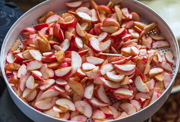 Sliced apples in white round plastic lot for drying