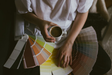 Fototapeta na wymiar Woman choosing paint color from swatches and palette for house renovation and repair.