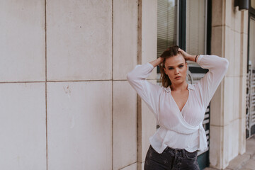 Portrait of a beautiful young caucasian girl in front of a white building