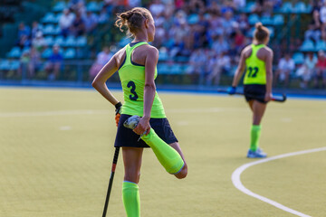 Obraz premium Young woman field hockey player stretching her leg
