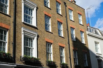 Fototapeta na wymiar Sunlit brick buildings with shadows on a street in London