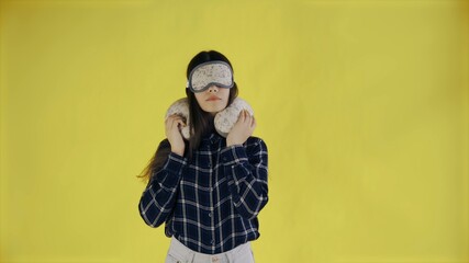 Young Woman Taking off Sleep Mask and Streching on yellow Background in Studio